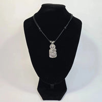 Silver pendant necklace on a black velvet stand against a white background