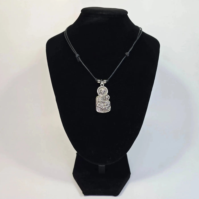 Silver pendant necklace on a black velvet stand against a white background
