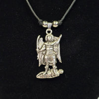 Silver angel pendant on a black cord against a black background